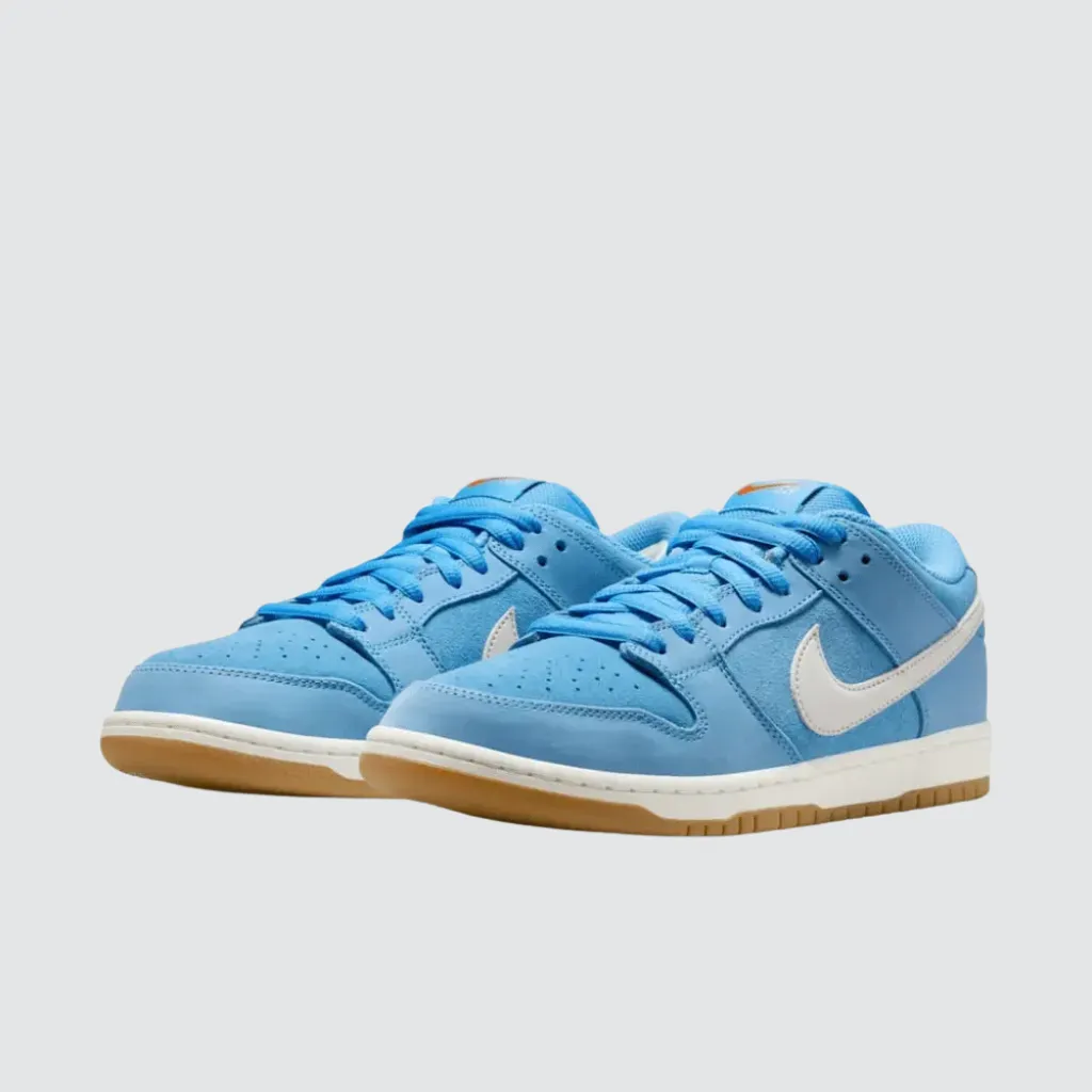Tênis Nike Dunk Low SB University Blue Gum com cabedal azul em malha, camurça e couro, Swoosh branco, marca no calcanhar e solado de borracha gum, representando um sneaker de skate com forte identidade streetwear.