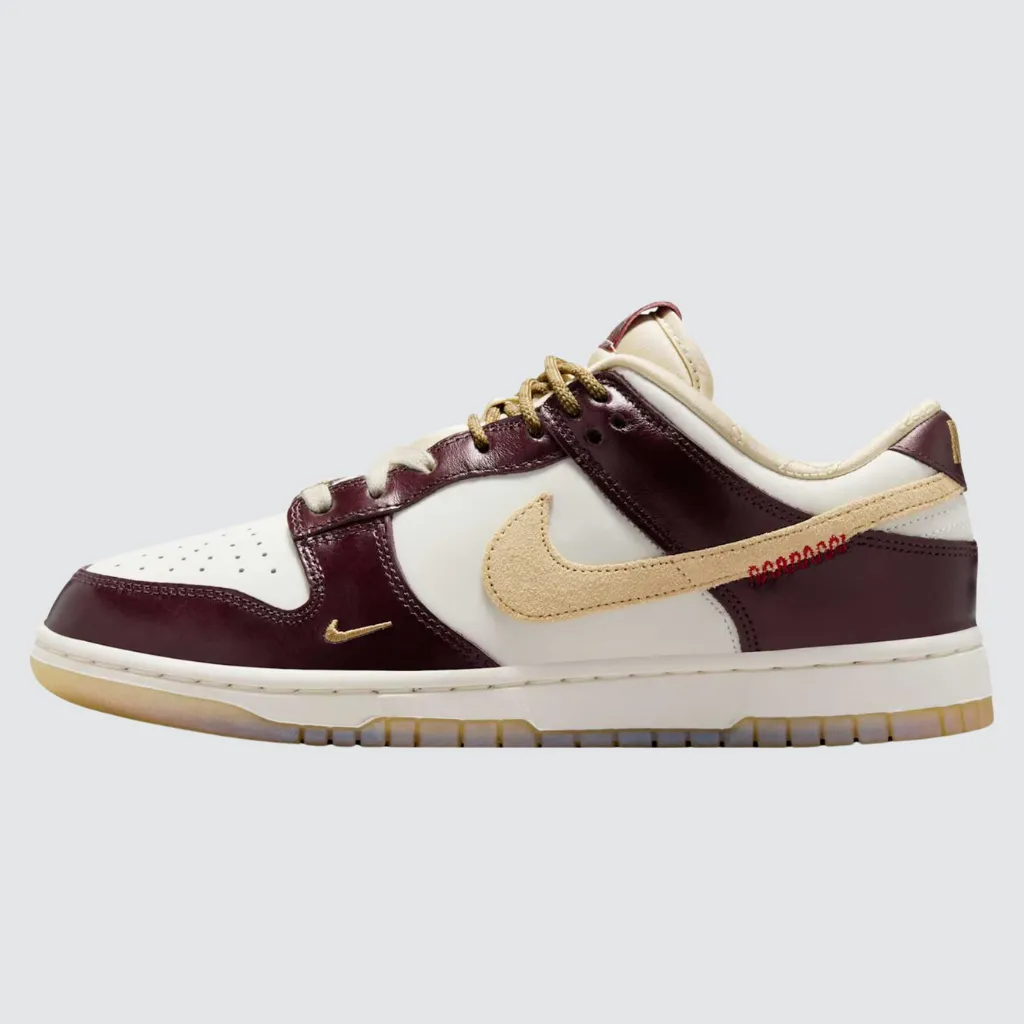 Tênis Nike Dunk Low Year of the Snake com cabedal em couro esbranquiçado, sobreposições borgonha, Swoosh em camurça bronzeada, detalhes em pele de cobra sintética na língua e solado translúcido, celebrando o Ano Novo Lunar com design simbólico e streetwear sofisticado.