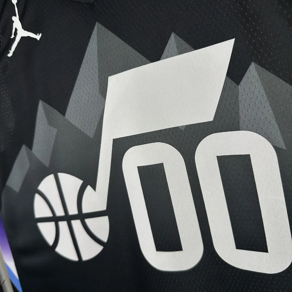 Imagem da Regata Utah Jazz Statement Edition 2025/26 Swingman Nike em preto, com logotipo Jazz Note centralizado no peito, gráfico de montanhas ao fundo, detalhes em roxo e azul claro na gola e nos painéis laterais, tecido mesh respirável, caimento regular e acabamento NBA.