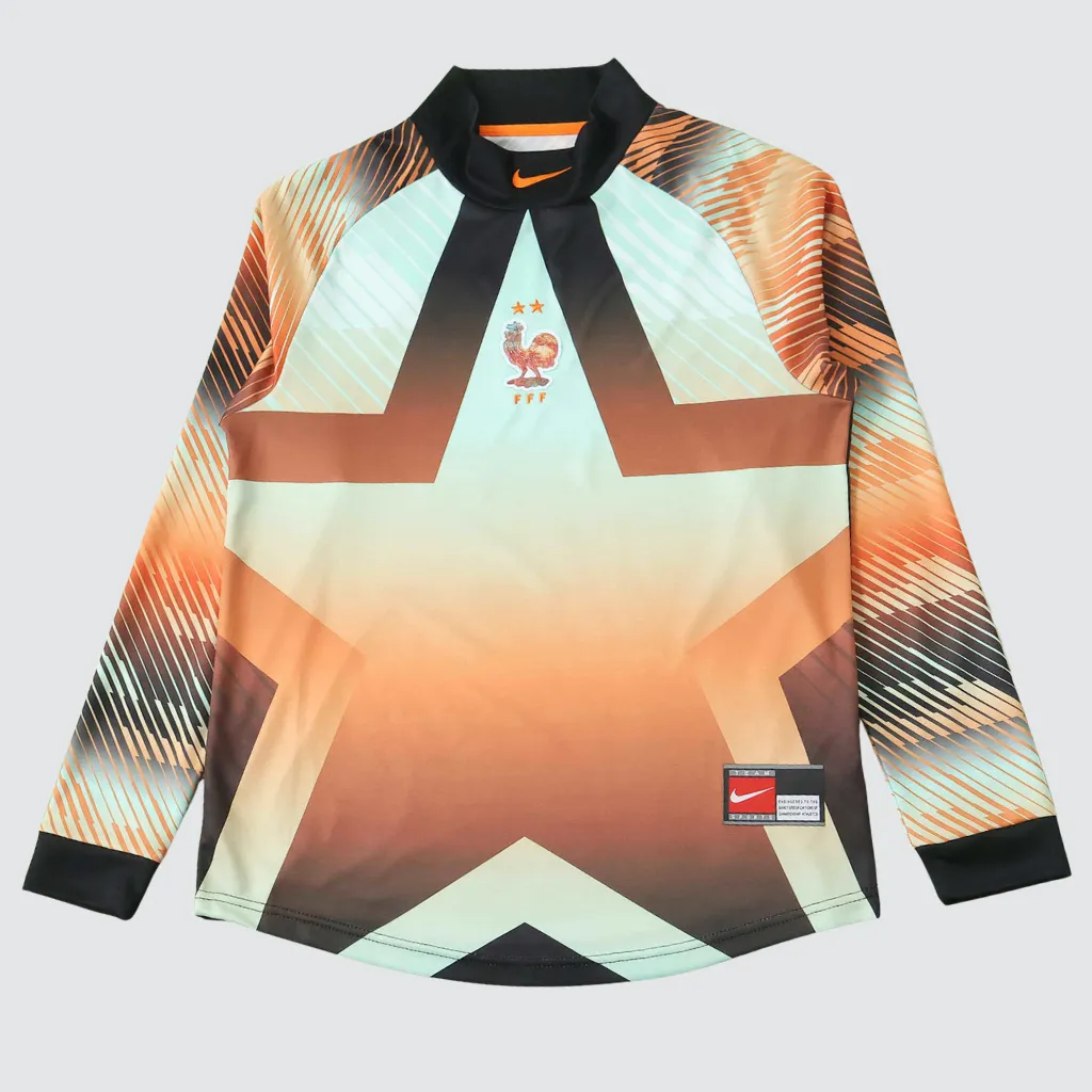Camisa de goleiro da Seleção Francesa Nike 2026 manga longa com design degradê em verde menta e laranja, escudo dourado com duas estrelas e visual moderno inspirado nos anos 2000.