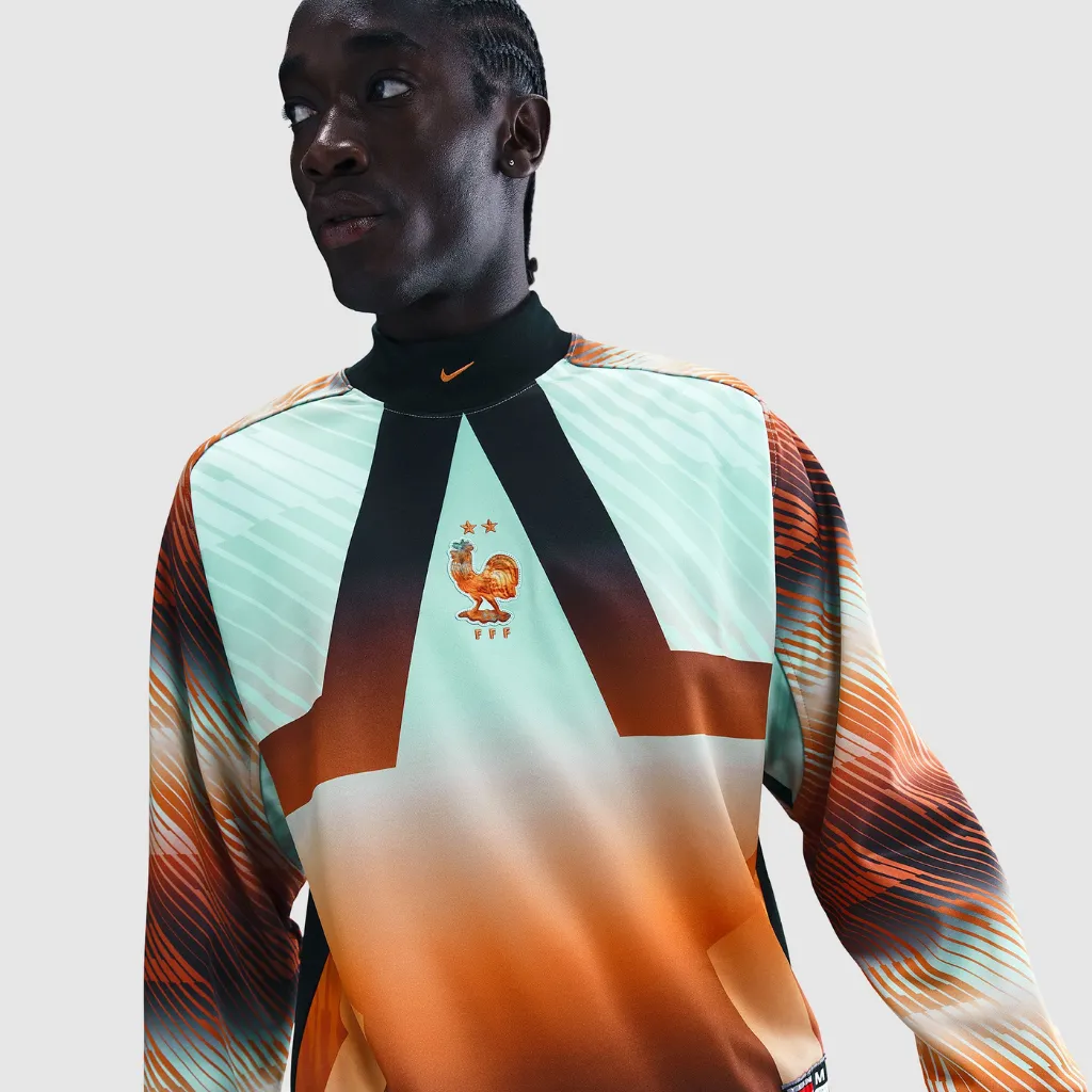 Camisa de goleiro da Seleção Francesa Nike 2026 manga longa com design degradê em verde menta e laranja, escudo dourado com duas estrelas e visual moderno inspirado nos anos 2000.