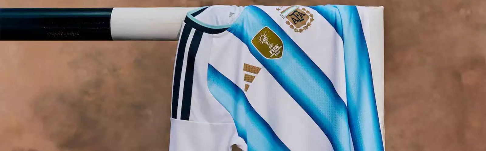 Camisa titular seleção argentina 2026 adidas branca com listras azul celeste e detalhes dourados, inspirada nos três títulos mundiais.