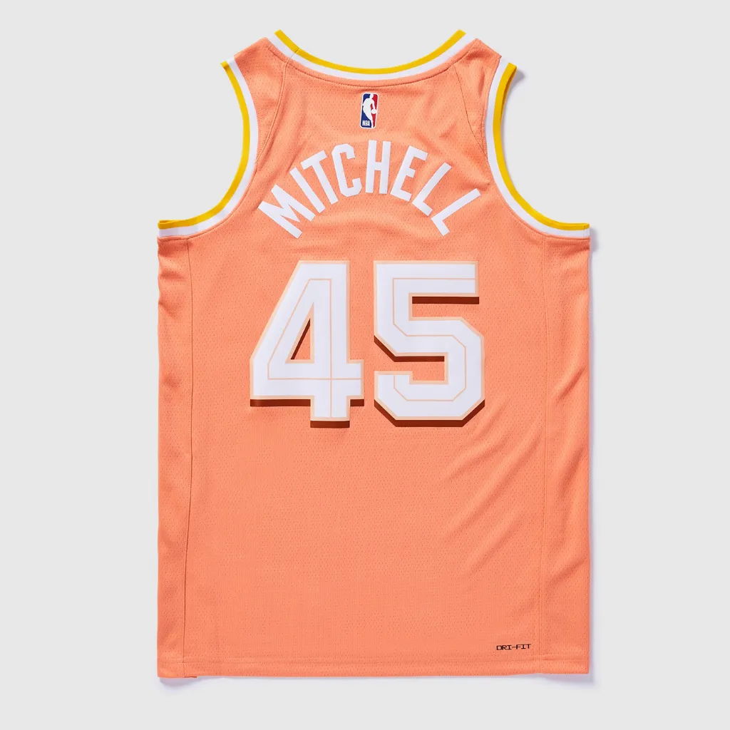 Regata Cleveland Cavaliers City Edition 2025/26 Swingman Nike em laranja pêssego, com inscrição THE LAND em branco no peito, gola V branca com detalhes em amarelo, tecido mesh respirável, caimento regular e acabamento NBA.