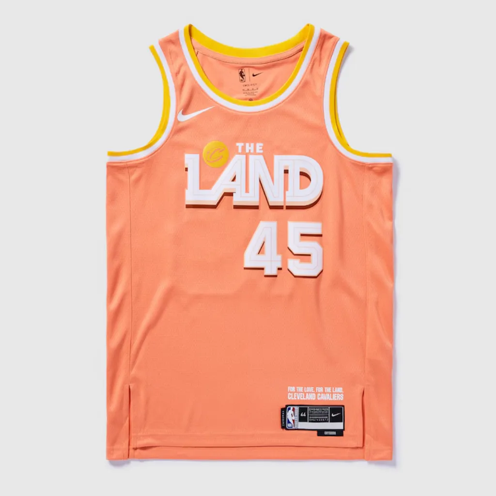 Regata Cleveland Cavaliers City Edition 2025/26 Swingman Nike em laranja pêssego, com inscrição THE LAND em branco no peito, gola V branca com detalhes em amarelo, tecido mesh respirável, caimento regular e acabamento NBA.