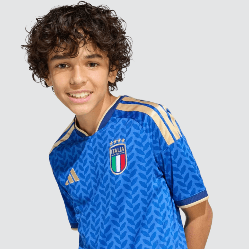 Conjunto infantil seleção italiana 2026 adidas azul e branco com detalhes dourados e calção branco.